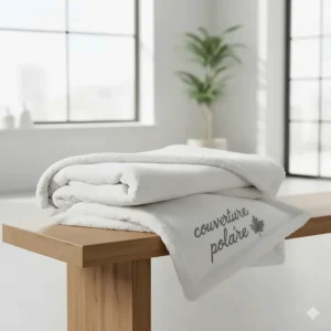 Luxury white sherpa fleece throw blanket, known in Canada as a couverture polaire, folded on a minimalist wooden bench.