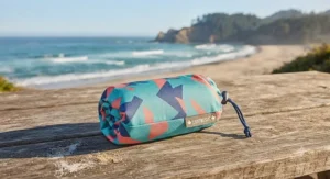 A lightweight beach blanket under $40 CAD packed inside its compact travel pouch.