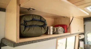 Compact RV blanket tucked away in an overhead camper cabinet, demonstrating space-saving storage solutions for Canadian road trips.