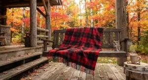 Traditional red and black plaid rustic cottage blanket spread across a porch swing during a colourful Canadian autumn.
