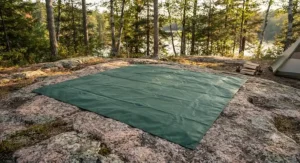 A durable, waterproof oversized camping blanket for two people laid across a granite shield campsite in an Ontario provincial park.