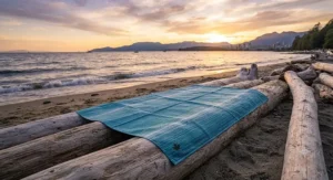 Breathable quick dry beach blanket laid out on driftwood by the Pacific Ocean during a sunset in Vancouver.