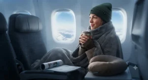 A passenger staying warm with a soft airline travel blanket during a chilly winter flight across Canada.