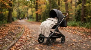 An infant staying warm under one of the best stroller blankets for babies featuring a soft knit texture on an autumn day