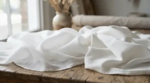 A white photography backdrop blanket displayed alongside a traditional muslin cloth to compare softness and drape.